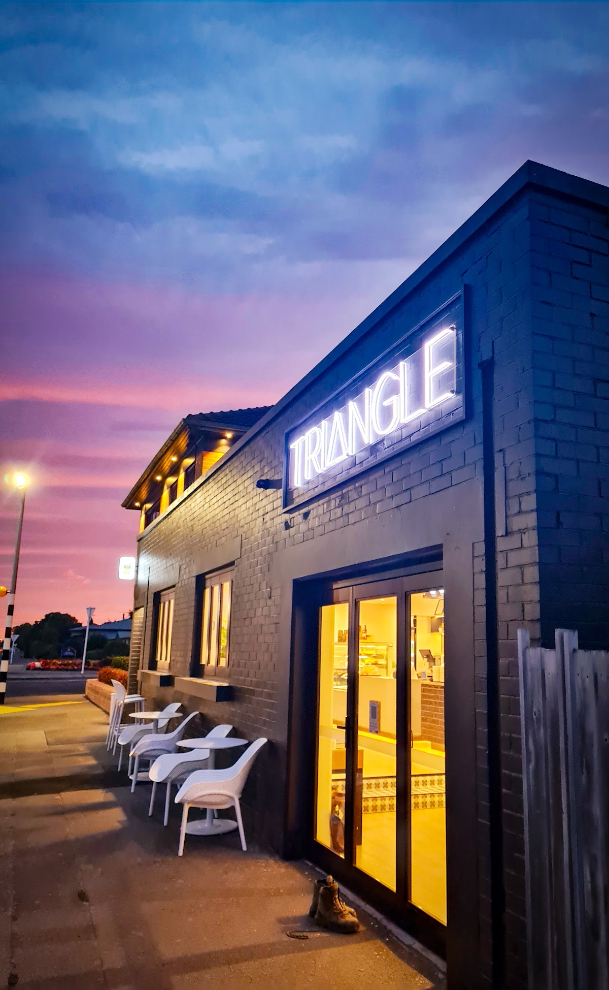 Triangle Espresso storefront lit by its neon sign at dusk